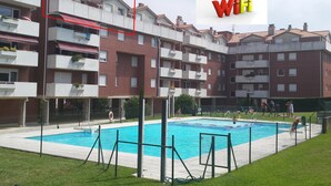 A residential building with a swimming pool, balconies, and a WiFi symbol. - Penthouse 100m² with Terrace and Pool (Castro Urdiales)