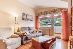 A living room with a sofa, armchair, and a coffee table. There is a painting on the wall and a window with curtains. - Penthouse 100m² with Terrace and Pool (Castro Urdiales)
