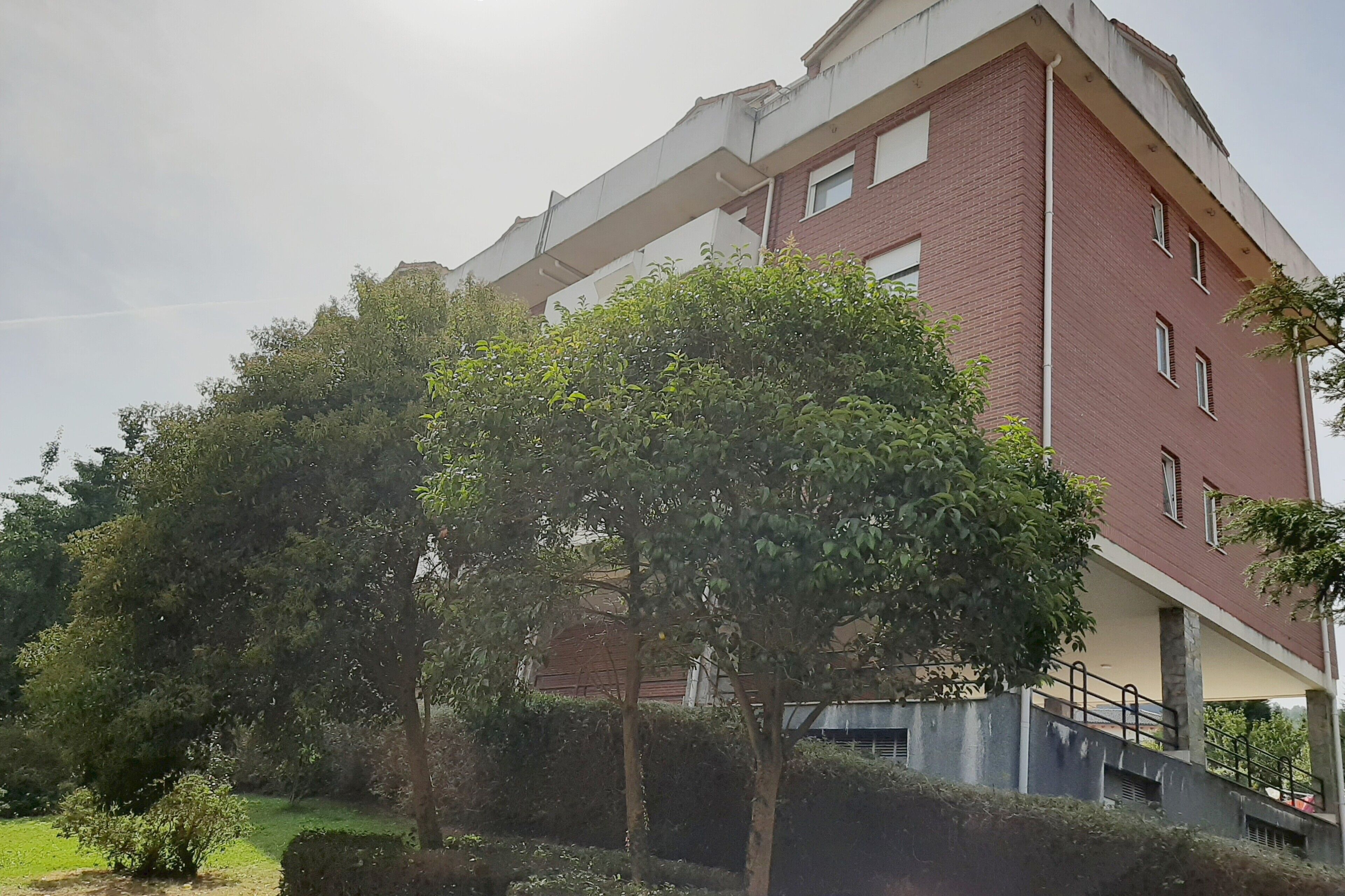 Een meerhoog gebouw met een bakstenen gevel, een overdekte doorgang en omliggend groen.