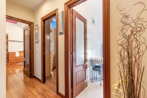 A hallway with wooden doors, a staircase, and a dining area with a chair. - Penthouse 100m² with Terrace and Pool (Castro Urdiales)