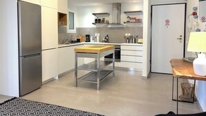 Uma cozinha moderna com eletrodomésticos de aço inoxidável, uma ilha central e um espaço de jantar com mesa e cadeiras.