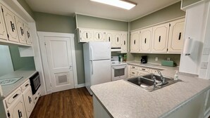 A kitchen with white cabinets, a refrigerator, a stove, and a sink.