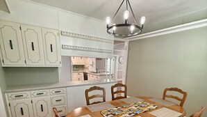 A dining area with a wooden table, four chairs, and a chandelier.