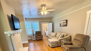 A living room with a fireplace, a ceiling fan, and a television on a stand.