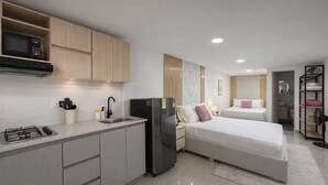 A compact hotel room with a kitchenette, a bed, a bedside table, a mirror, and a wardrobe. - Comuna 13 Urbana | 1-minute walk to the metro + Coworking (Medellín)
