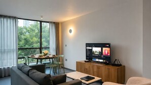 Una sala de estar moderna con sofá, sillón, mesa de centro y televisor sobre un mueble de madera.