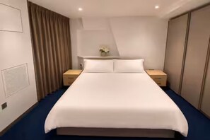 A hotel room with a large bed, two bedside tables, a nightstand, a dresser, and a curtain. - 2 Bedroom Flat, 1 Bathroom, furnished living room. (London)