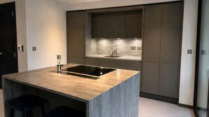 Una cocina moderna con una isla central, muebles oscuros y un ventanal grande.