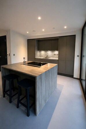 A modern kitchen with a central island, dark cabinetry, and a large window. - 2 Bedroom Flat, 1 Bathroom, furnished living room. (London)
