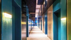 Ein Korridor mit Teppichboden, blauen Wänden und einer Decke mit sternförmigen Lichtern.