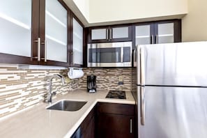 Una cocina moderna con electrodomésticos de acero inoxidable, armarios de madera oscura y salpicadero de azulejos.