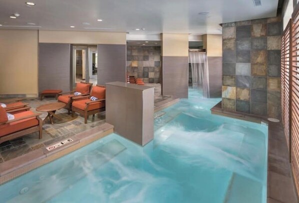 A spa area with a hot tub, seating, and a stone wall.
