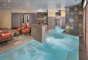 Un área de spa con jacuzzi, asientos y una pared de piedra.