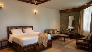 A bedroom with a large bed, a sofa, a chair, a small table, and a stone wall. - Premium King Bed Room Palette Hotel Amritsar (Amritsar)