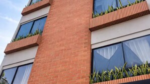 Un edificio de varios pisos con fachada de ladrillo, ventanas amplias y plantas verdes en jardineras.