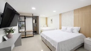Una habitación de hotel moderna con una cama grande, un televisor montado en la pared, un armario y una mesita de noche.
