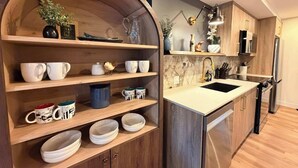 A modern kitchen with wooden shelves, a marble backsplash, and stainless steel appliances.