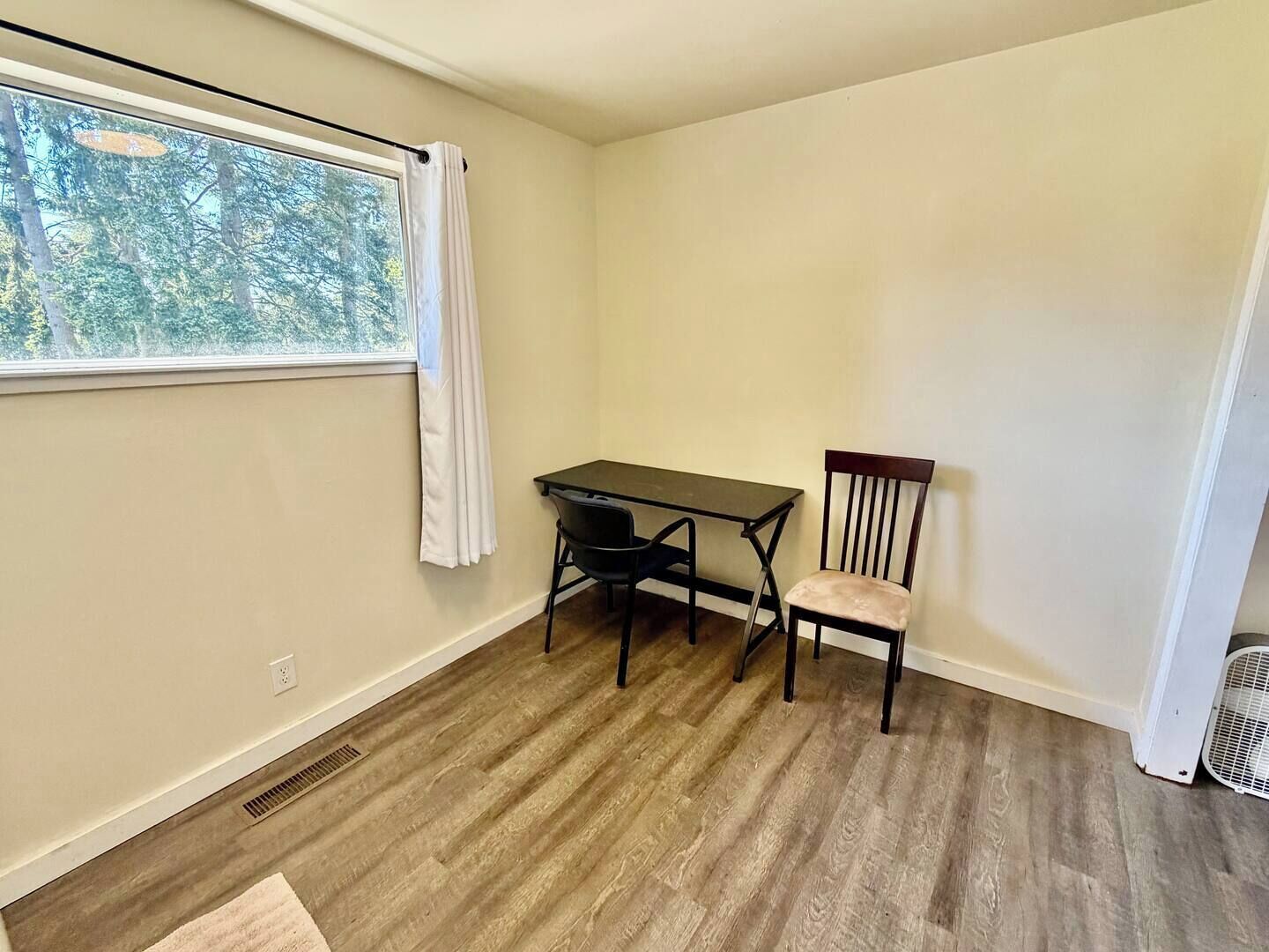 A room with a window, a table, a chair, and a radiator.