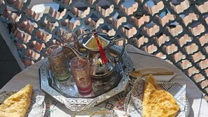 Ein Tisch, gedeckt mit einem Tee-Service, Gläsern, einer Platte mit Speisen und einem kleinen Topfpflanzen.