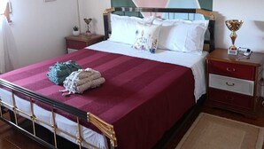 Ein Bett mit einem Kopfende mit geometrischem Muster, ein Nachttisch mit Lampe und eine wandmontierte Klimaanlage.