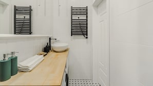 Ett modernt badrum med ett badrumsskåp i trä, en vit tvättställ och två handduksställ.