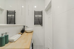 A modern bathroom with a wooden vanity, a white sink, and two towel racks. - Cozy City Center Apartment in Warszawa (Warsaw)