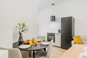 A modern kitchen with a dining area, featuring a refrigerator, oven, and dining table with chairs. - Cozy City Center Apartment in Warszawa (Warsaw)