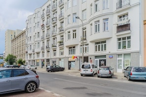 A multi-story building with balconies, a street in front, and parked cars. - Cozy City Center Apartment in Warszawa (Warsaw)