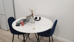 Un tavolo rotondo da pranzo con due sedie, un portatile, una lattina e un vaso decorativo con piante secche.