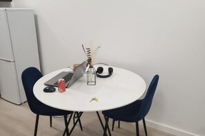 Ein runder Esstisch mit zwei Stühlen, einem Laptop, einer Dose und einer dekorativen Vase mit Trockenpflanzen.