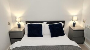 Un letto rifatto con due cuscini, due comodini con lampade e un quadro appeso al muro.