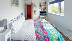 A modern bedroom with a bed, bedside table, and a window with a view. - Glastonbury Studio- Amazing Views and Free Parking (Glastonbury)
