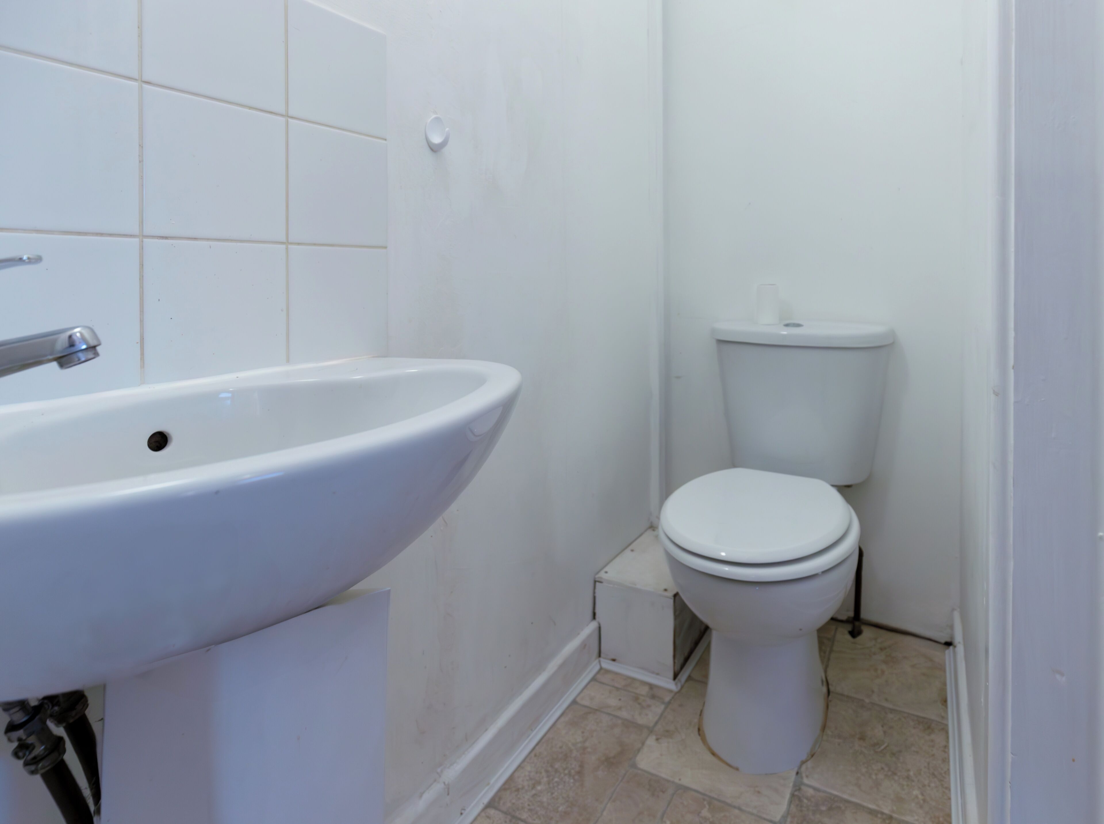 A bathroom with a white sink, toilet, and tiled floor.