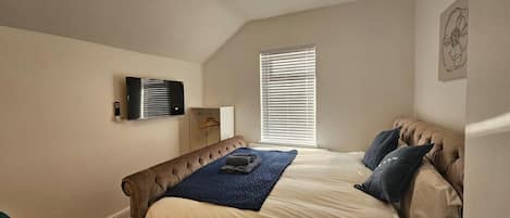 A bedroom with a bed, a ceiling fan, a window with blinds, and a wall-mounted air conditioning unit.