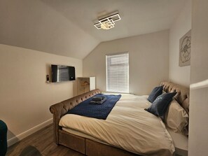 A bedroom with a bed, a wardrobe, a TV, and a window with blinds. - Cozy Studio - Sleeps 2 - Cardiff City Centre (Cardiff)