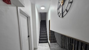 Ein Flur mit Marmorboden, einer Treppe, einer weißen Tür und einer Wanduhr.