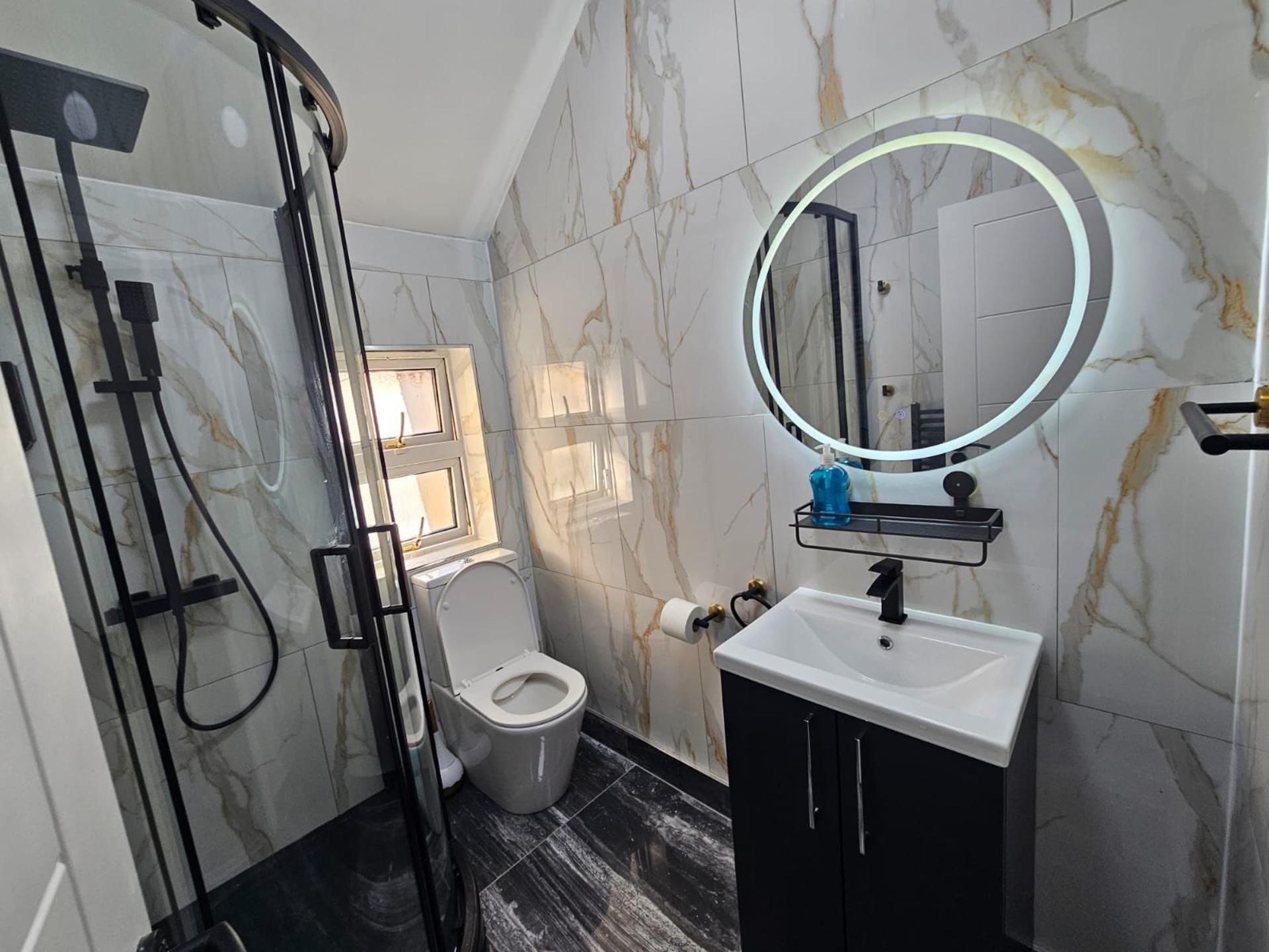 Ein Badezimmer mit Toilette, Waschbecken, Spiegel und Dusche.