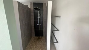 A narrow, tiled shower area with a built-in shelf unit.