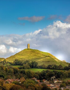 A hilltop with a tower, surrounded by greenery and a village at its base. - Glastonbury - Contactlesscheckin - Free Parking (Glastonbury)