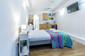 A compact hotel room with a bed, bedside table, lamp, and a view of the kitchen area. - Glastonbury - Contactlesscheckin - Free Parking (Glastonbury)