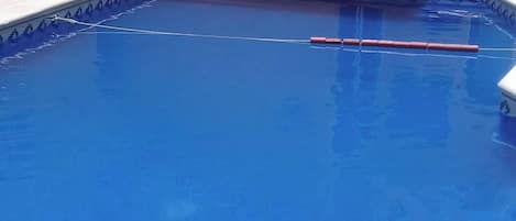 A swimming pool with a blue interior, surrounded by a tiled deck.