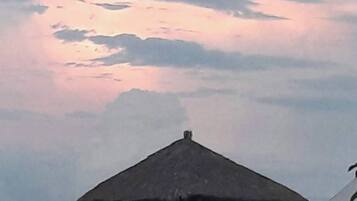 Una estructura con techo de paja en la azotea, posiblemente un pabellón o mirador, con vistas a un cielo nublado.