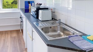 Une cuisine moderne avec un évier en acier inoxydable, un grille-pain et une planche à découper bleue.