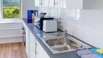 A modern kitchen with a stainless steel sink, a toaster, and a blue cutting board.