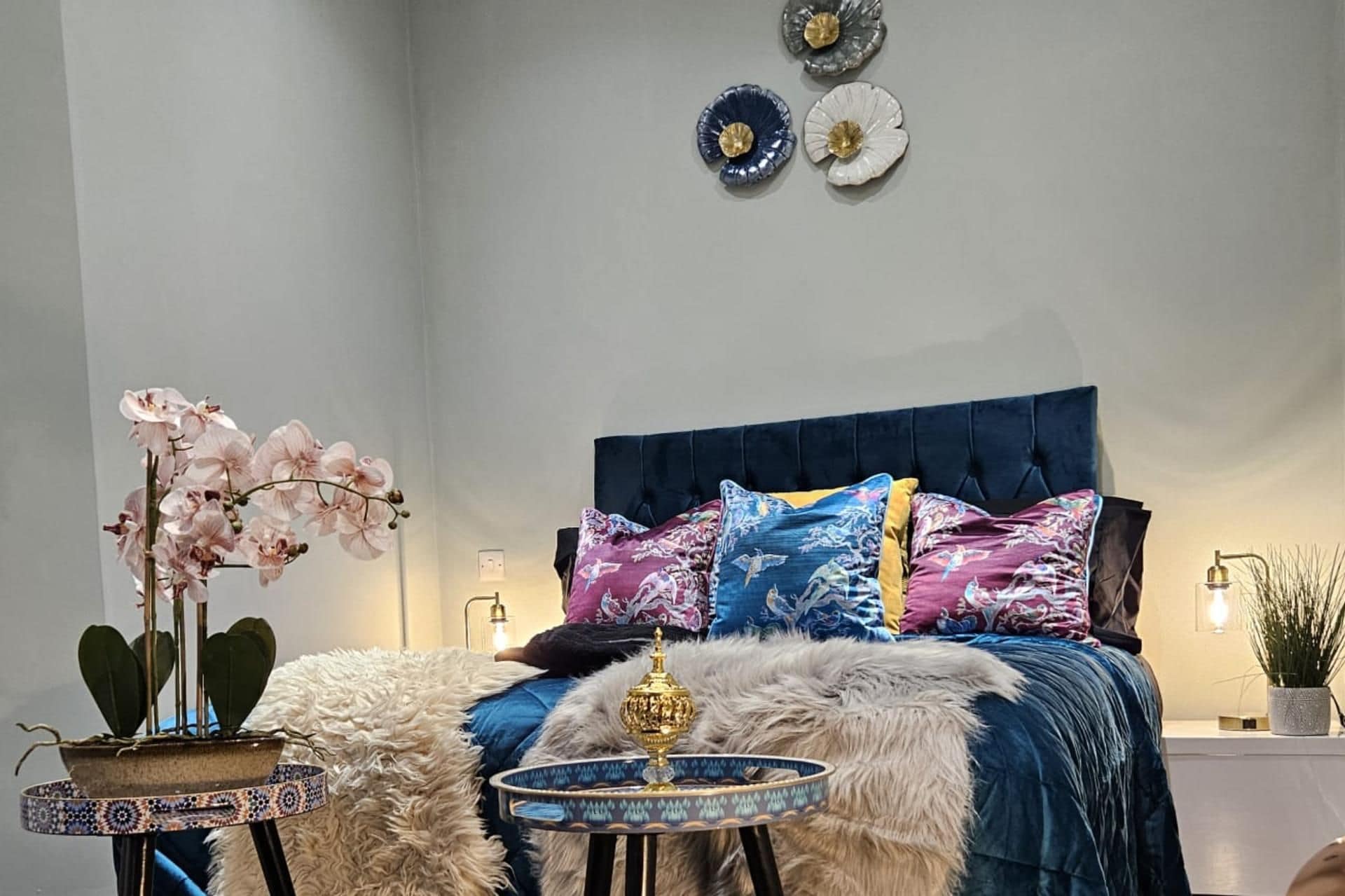 A bedroom with a bed, decorative pillows, a nightstand, a lamp, and wall art.