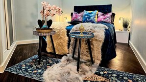 A bedroom with a bed, a small side table with a plant, a decorative bowl, and a rug. - Airport Stays - Deluxe Studio London Heathrow (Hayes)