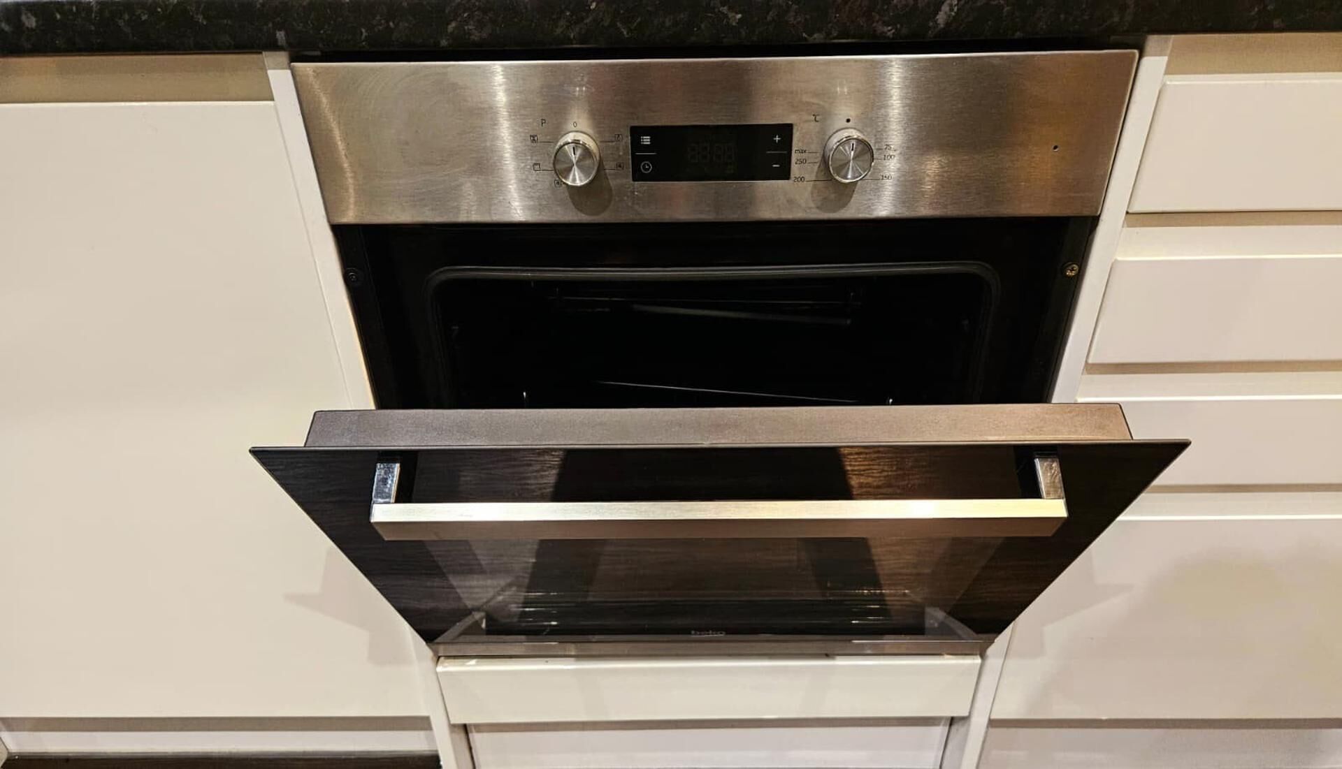 An oven with a digital display and two control knobs, built into a kitchen cabinetry.