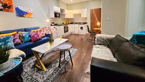 A modern living room with a sofa, coffee table, and a small rug. - Airport Stays - Deluxe Studio London Heathrow (Hayes)