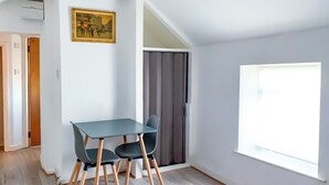 Huoneessa on sänky, pöytä tuoleineen, ikkuna ja ovi.