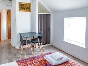 Ein Zimmer mit einem Bett, einem Tisch mit Stühlen, einem Fenster und einer Tür.